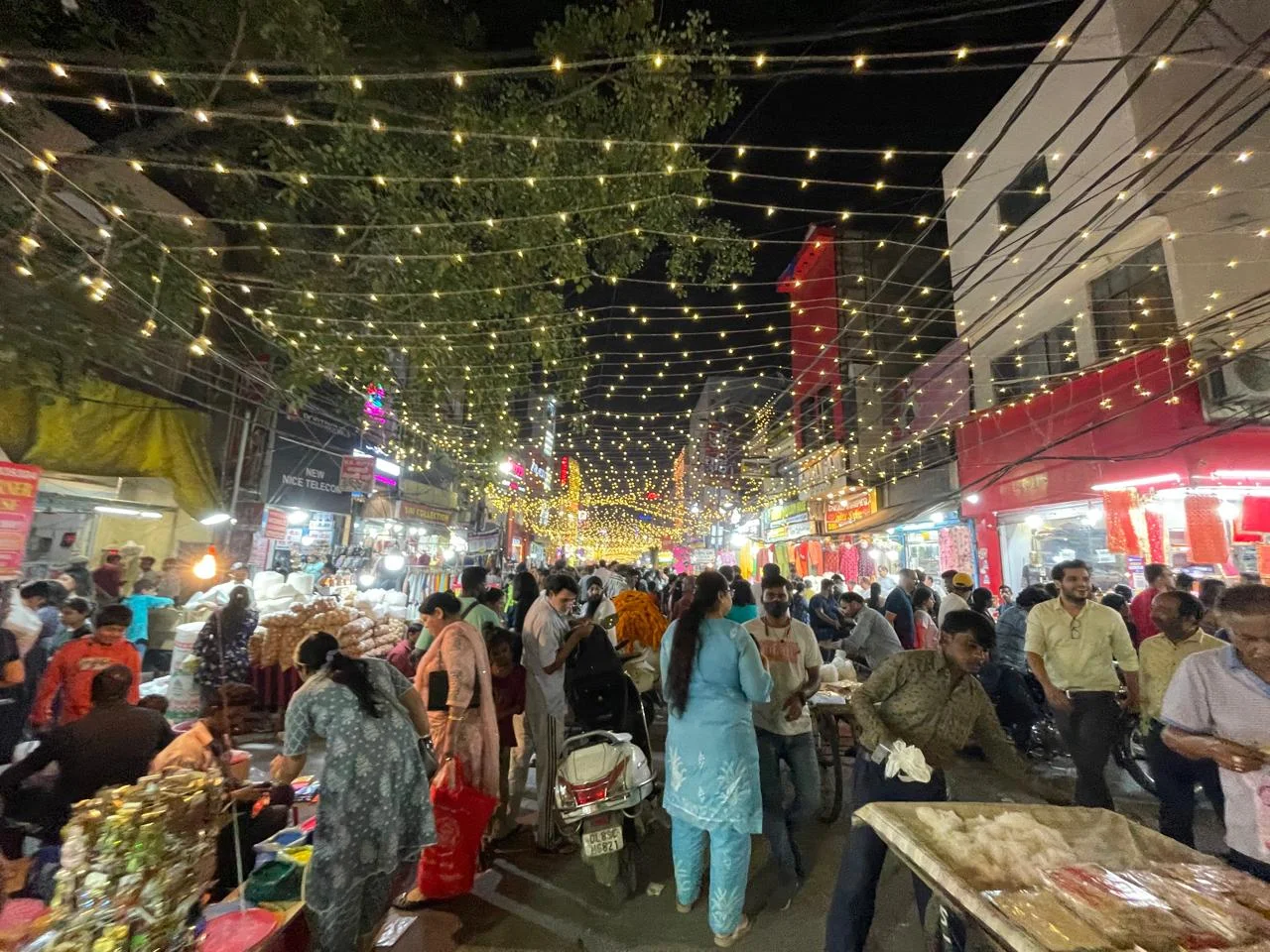 Crowded Indian market decorated with festive lights during the Diwali shopping season.